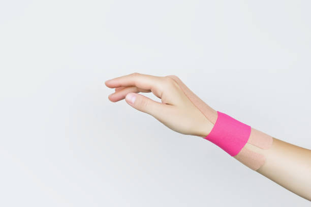 fixation of the wrist joint of a female hand with beige and pink kinesio tape - sprain human joint palm human arm ストックフォトと画像