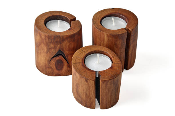istock Three wooden candlesticks from a cut tree with a crack with candles isolated on a white background 1850461547