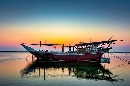 Golden hues paint the tranquil Dammam seaside as boats rest against the morning glow, a serene embrace of nature's beauty in Saudi Arabia.