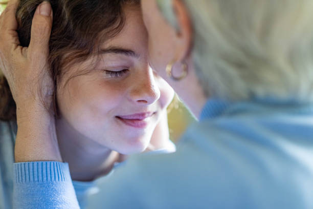 grandmother kisses her granddaughter on the head grandmother kisses her granddaughter on the head, close up girls happy face teenage girl with grandmother stock pictures, royalty-free photos & images