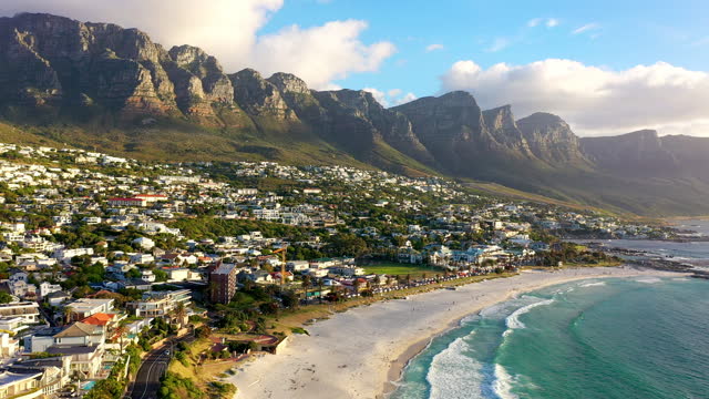 Drone of beach, mountains and houses for vacation, holiday and travel or tourism destination with eco landscape. Aerial view of urban city location, ocean and sunset at sea in Cape Town, South Africa