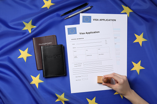 Immigration to European Union. Woman stamping visa application forms on flag, top view