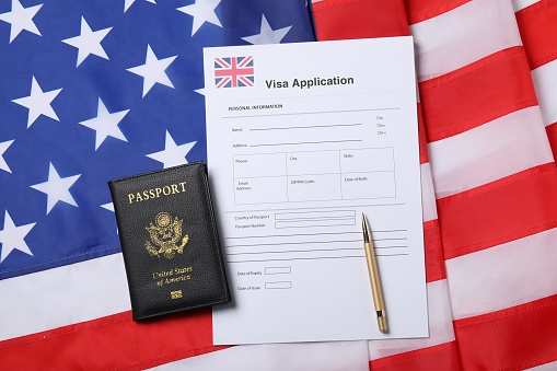 Immigration to USA. Visa application form, passport and pen on flag, flat lay