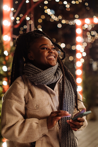 The young woman texts Christmas greetings from her smartphone