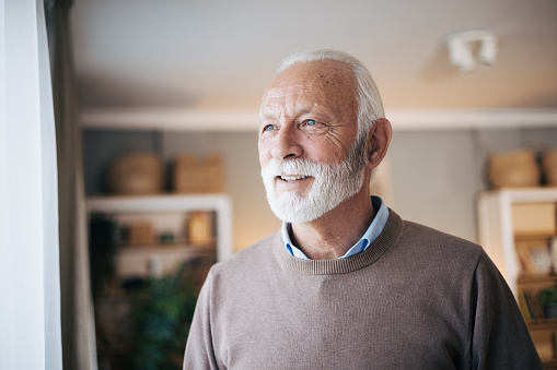 Portrait of a senior man looking out of window at home