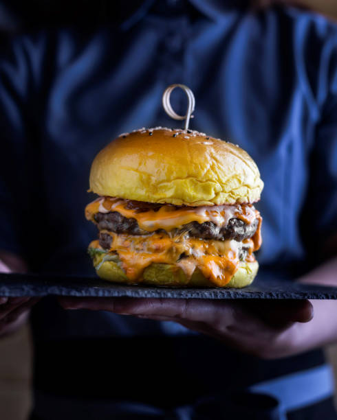 istock Special Double Decker Burger with melted cheese and lettuce leaves served in cutting board in holding hand isolated on wooden table side view of arabic food 1850556243