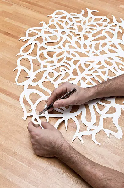 An artist engraving a paper block to create a tree pattern