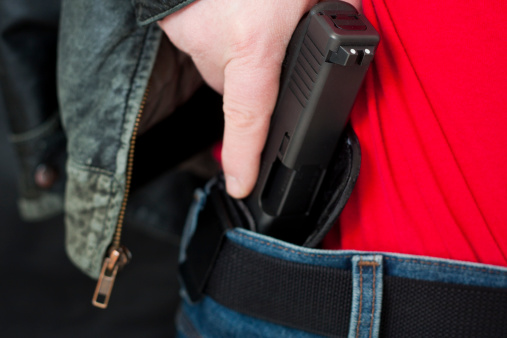 A caucasian man drawing his modern polymer (Glock) .45 caliber pistol from an IWB (inside the waistband) holster under his leather jacket.  Showing proper trigger control by keeping his finger off the trigger as he draws.All images in this series...