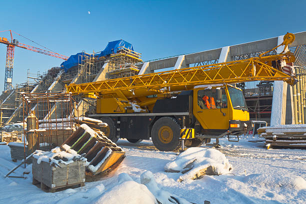 Mobile Crane in Construction Site Winter scene with Mobile Crane and a new sports hall under construction crane truck stock pictures, royalty-free photos & images