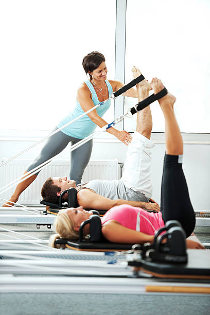 ayudar a las personas con entrenador de ejercicios de pilates. - gym machine smiling coach fotografías e imágenes de stock