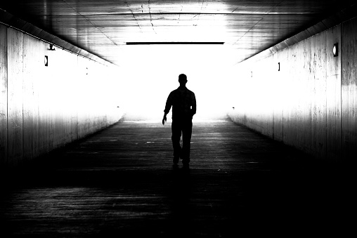 A man is walking out of the tunnel, black and white image. 