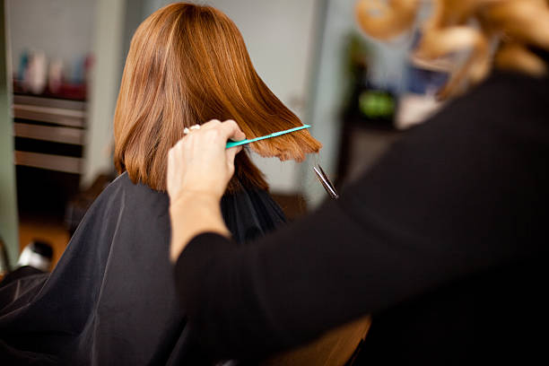 Little Red-Haired Girl Getting Haircut in Salon Color image of a little red-haired girl getting her hair cut by a young woman in a salon. Combing stock pictures, royalty-free photos & images