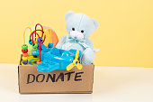 Donation, charity concept. Toy donation box with teddy bear, wooden and plastic educational toys on white desk