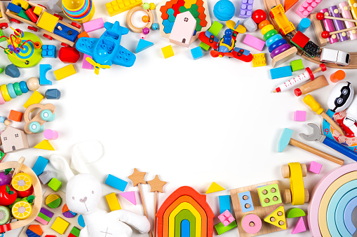 Baby kids toys frame. Set of colorful educational wooden and fluffy toys on white background. Top view, flat lay, copy space for text.
