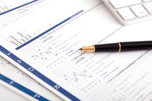 An employee 360 performance evaluation survey on desk with pen and keyboard.