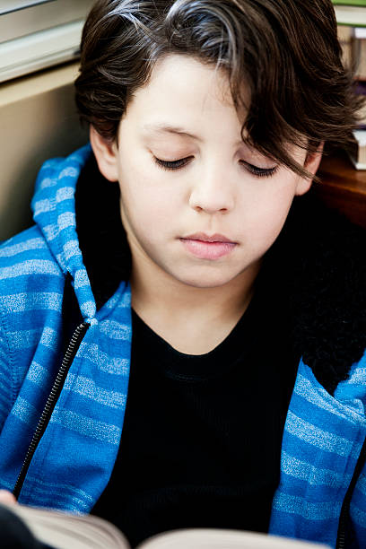 istock Young boy reading a book in by the window 185058990