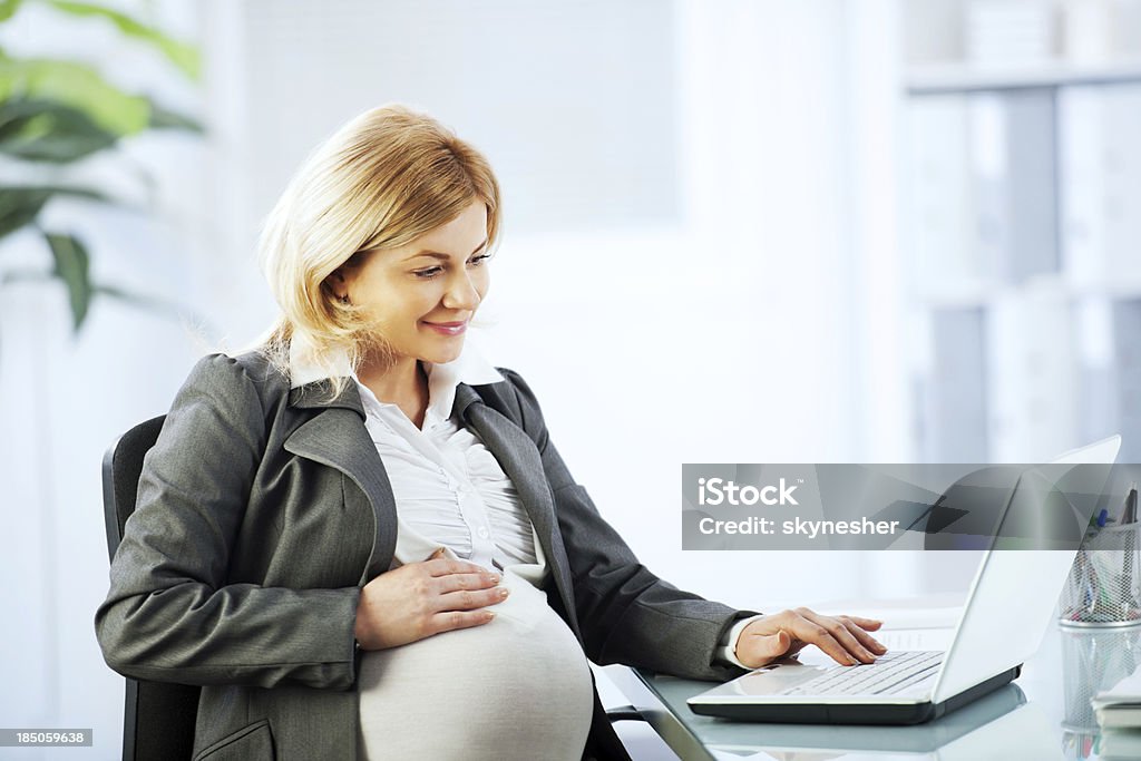 Ładna kobieta w ciąży pracuje na notebook. - Zbiór zdjęć royalty-free (Biuro)