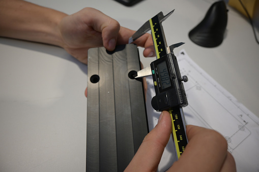 measuring the finished plastic product using a caliper.