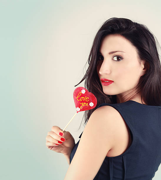 istock Girl holding a heart shaped lollipop 185060399