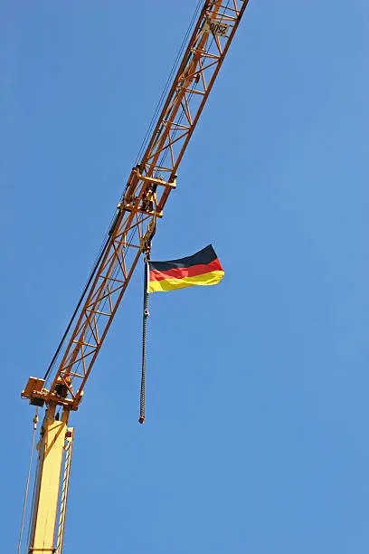 German flag on a crane at a construction site high up in the blue sky. Greetings for the soccer world championship 2010