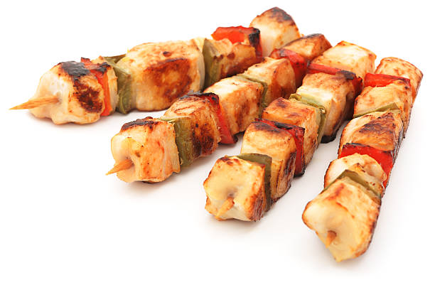 Four grilled chicken kabobs isolated on white
