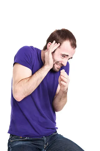 Young bearded Caucasian man partially hiding his face in a lighthearted ducking reaction to verbal abuse.