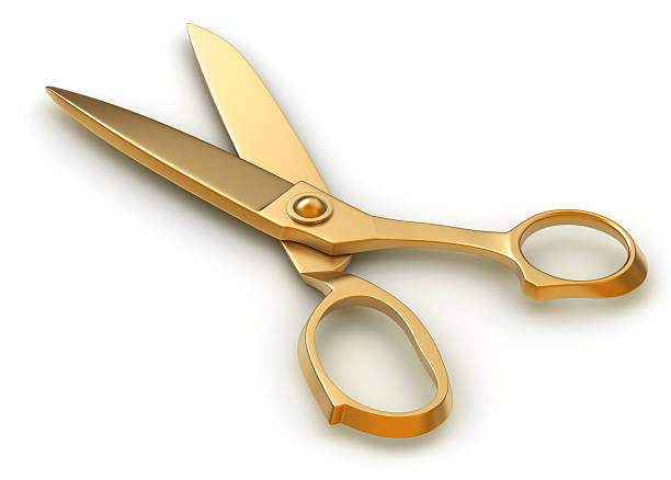 Pair of golden scissors on white surface stock photo