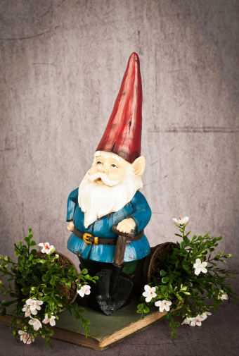 Garden gnome standing on old gardening book against scratched grungy background.