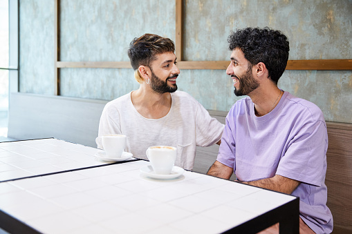Gay couple enjoying a coffee together. They are sitting in a coffee shop.