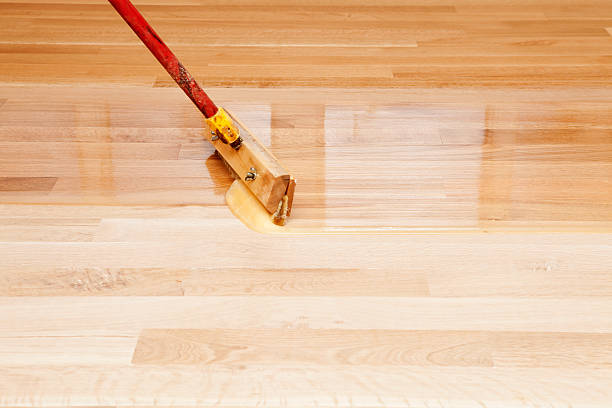 Squeegee Style Brush Applying Clear Polyurethane to Hardwood Floor stock photo
