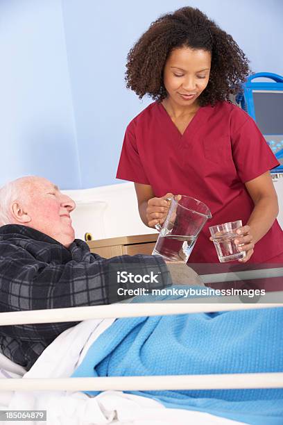 Медсестра Давая Стакан Воды До Старших Человек В Больнице — стоковые фотографии и другие картинки Пациент