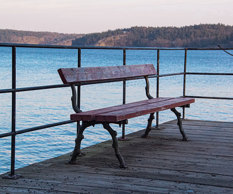 Close up of a park bench against a lake