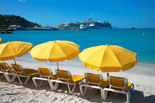 Great Bay beach, Philipsburg, St Maarten. Early morning, and the empty sun loungers await the  passengers from the many docked cruise ships seen in the background.
