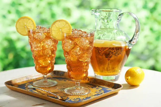 Two glasses of iced tea with pitcher.  Selective focus.