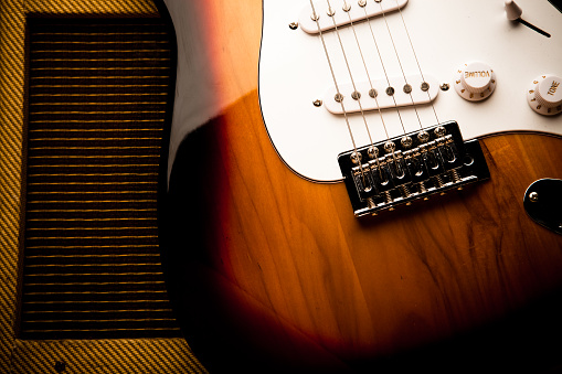 Still life of a mid-20th-century electric guitar leaning against a vintage amplifier