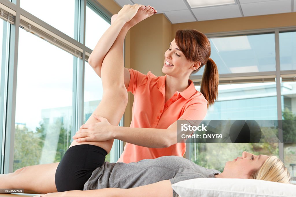 Kinésithérapeute aider une femme stretch sa jambe - Photo de Hanche libre de droits