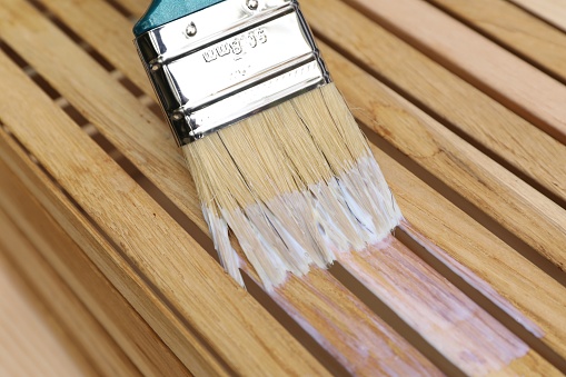 Applying varnish onto wooden crate with brush, closeup view