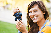 Cheerful young woman eating grapes