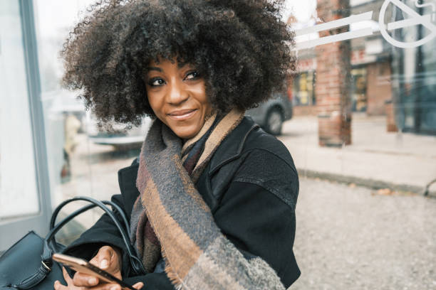 African female registered nurse on the way to work. She is wearing  medical scrubs under winter coat. Urban exterior of busy street in Toronto, Canada.