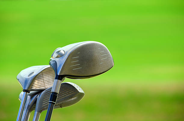 Golf clubs glistening in the sunlight. A golf bag full of clubs. Golf club heads.
