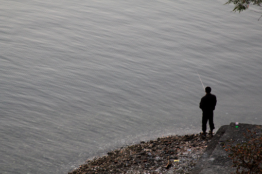 man fishes in the sea in Wonsan, North Korea, DPRK