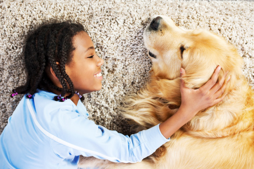 Girl and dog playing on the carpet.