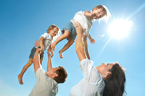 istock Parents joyfully throwing their children in the air 185070769