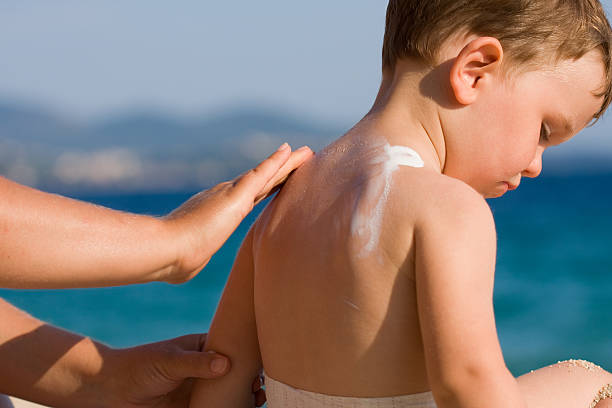istock Woman applying sunscreen on a child's back at the beach 185070995
