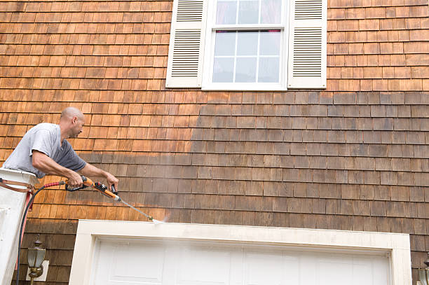 Man Power Washing exterior shingles Man in a bucket truck power washing exterior shingles. house washing stock pictures, royalty-free photos & images