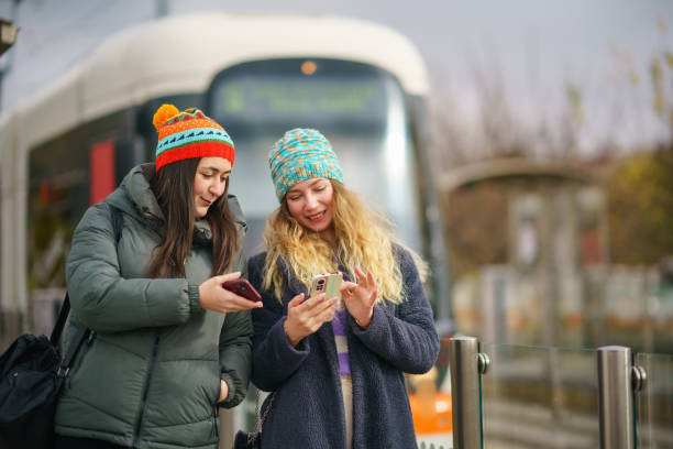 istock Two women using mobile phone at the tramway station 1850717703