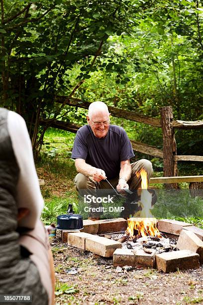 Foto de Homem Velho Feliz Cozinhar Na Fogueira De Acampamento e mais fotos de stock de Fogueira - Fogo ao Ar Livre