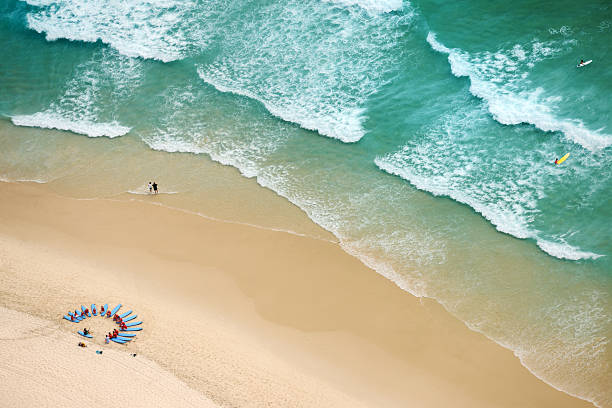 Young woman sitting on the rock edge on Sunrise Beach at Noosa Heads in Queensland, Australia.
