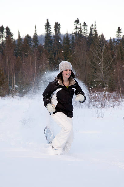 femme cours'en raquettes dans la poudreuse - winter snowshoeing running snowshoe photos et images de collection