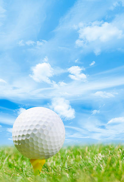 istock White golf ball and tee, grass course and blue sky 185073448